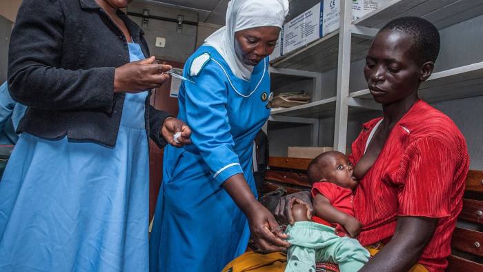 A Health Surveilance Assistant (HAS) prepares to give malaria vaccine to a child as Hanifa Likaka (C), a Senior Nursing Officer and Matron for the vaccine launch venue hospital, assists in removing a child's trousers for easy injection April 23, 2019 at Mitundu Community hospital in Malawi's capital district of Lilongwe on the first day of the Malaria vaccine implementation pilot programme in Malawi aiming to immunise 120,000 children aged two years and under to assess the effectiveness of the pilot vaccine and whether the delivery process is feasible. - Malawi spearhead today large scale pilot tests for the world's most advanced experimental malaria vaccine in a bid to prevent the disease that kills hundreds of thousands across Africa each year. After more than three decades in development and almost $1 billion in investment, the cutting-edge trial will be rolled out in Malawi's capital Lilongwe this week and then in Kenya and Ghana next week. (Photo by AMOS GUMULIRA / AFP) (Photo credit should read AMOS GUMULIRA/AFP via Getty Images)