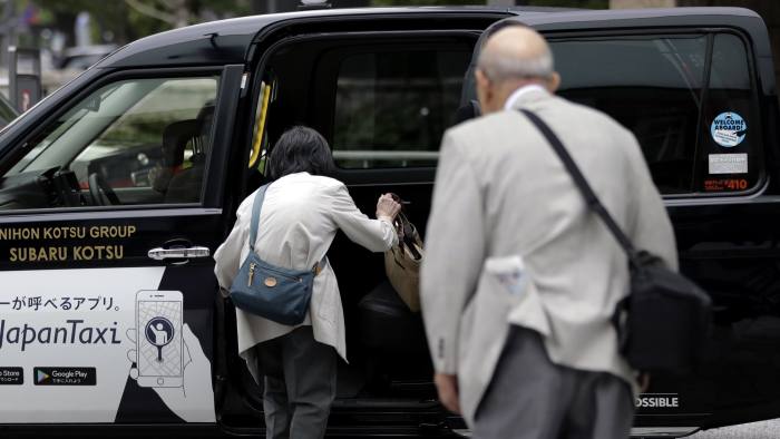 An woman boards a taxi in Tokyo, Japan, on Tuesday, July 9, 2019. Japan’s wages dropped for a fifth month, according to Japan's Ministry of Health, Labour and Welfare, adding to concerns over the resilience of consumer spending as a sales tax increase approaches in October. Photographer: Kiyoshi Ota/Bloomberg