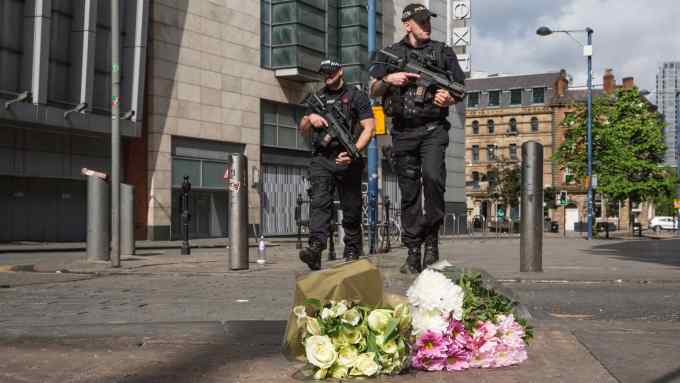 MANCHESTER, ENGLAND - MAY 23: Armed police patrol on Shudehill walking past the first floral tributes to the victims of the terrorist attack on Shudehill, May 23, 2017 in Manchester, England. An explosion occurred at Manchester Arena as concert goers were leaving the venue after Ariana Grande had performed. Greater Manchester Police are treating the explosion as a terrorist attack and have confirmed 22 fatalities and 59 injured. (Photo by Christopher Furlong/Getty Images)