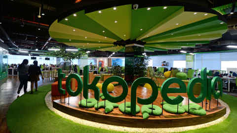 The PT Tokopedia logo is displayed at the company's offices in Jakarta, Indonesia, on Friday, Feb. 19, 2016. Tokopedia's Chief Executive Officer William Tanuwijaya was helping small companies build websites when he began shopping an idea for Indonesia's first Internet shopping hub. It took 11 pitches to get funding, but his startup is now verging on becoming the nation's first unicorn. Photographer: Dimas Ardian/Bloomberg