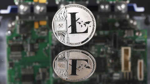 A coin representing Litecoin cryptocurrency sits reflected on a polished surface and photographed against a computer circuit board in this arranged photograph in London, U.K., on Thursday, Feb. 8, 2018. Cryptocurrencies tracked by Coinmarketcap.com have lost more than $500 billion of market value since early January as governments clamped down, credit-card issuers halted purchases and investors grew increasingly concerned that last year’s meteoric rise in digital assets was unjustified. Photographer: Luke MacGregor/Bloomberg
