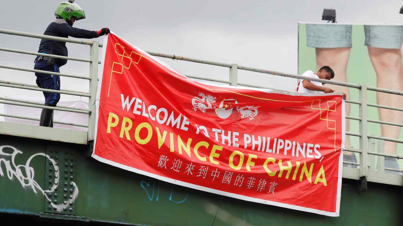 Traffic enforcers remove an anti-China banner hanging on an overpass in Metro Manila on July 12.