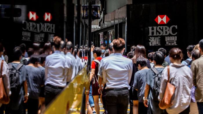Pedestrians walk past the logo for HSBC outside a local branch bank in Hong Kong