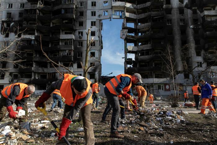 Volunteers in hi-vis jackets sweep up rubble