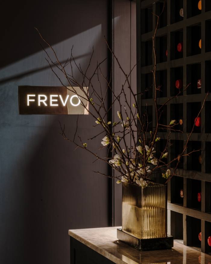Gubahan bunga di hadapan bekas wain di sebelah papan tanda logam yang tertera 'Frevo'