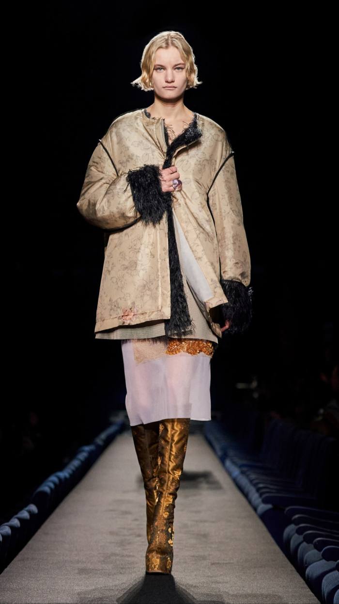Model in loose jacket, knee-length skirt and boots