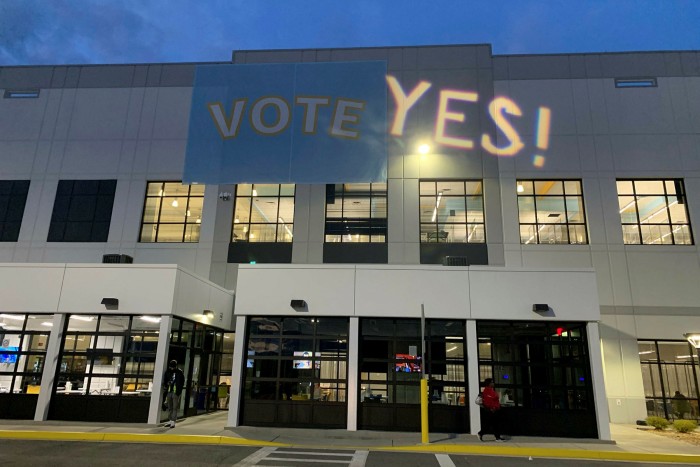 The word ‘Yes!’ is projected next to the ‘Vote’ sign at an Amazon warehouse in Bessemer, Alabama