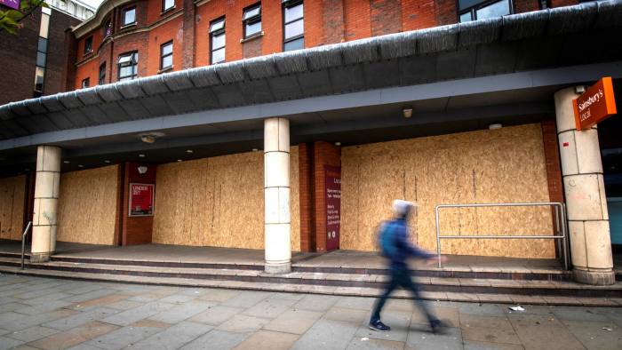 A man walks past a boarded-up Sainsbury’s store in central Manchester