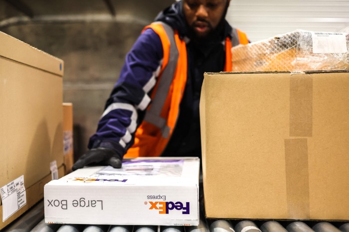 A FedEx employee loads packages at an aircraft container