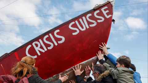 Protesters hold a boat with ‘Crisis Suisse’ written on it in Zurich