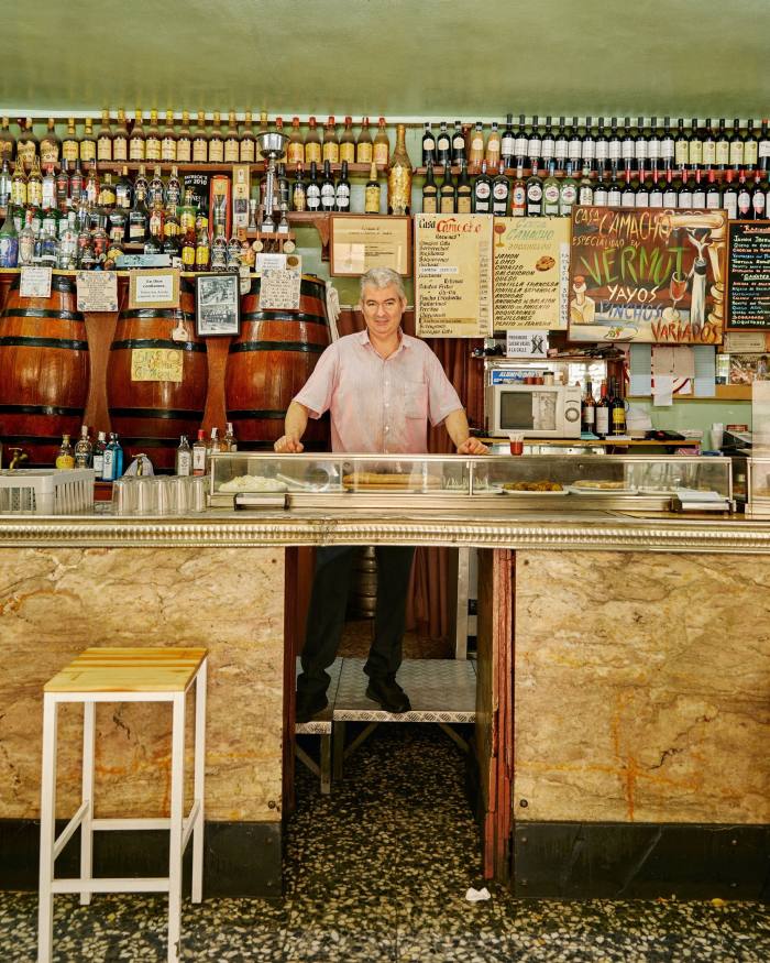 Chủ sở hữu Casa Camacho Miguel Ángel Gonzalez Pérez phía sau quầy bar của mình, với những chiếc thùng nhỏ trên bức tường bên trái