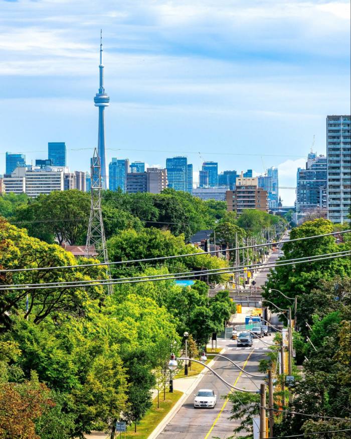 El horizonte de Toronto y la torre CN, con una carretera y un parque en primer plano, vistos desde lo alto de los 110 escalones que conducen a Spadina House