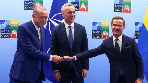 Turkish President Tayyip Erdogan and Swedish Prime Minister Ulf Kristersson shake hands next to NATO Secretary-General Jens Stoltenberg