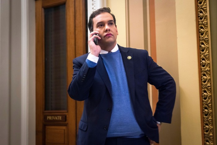 Politician George Santos stands outside the House chamber talking on a phone in Washington, DC 