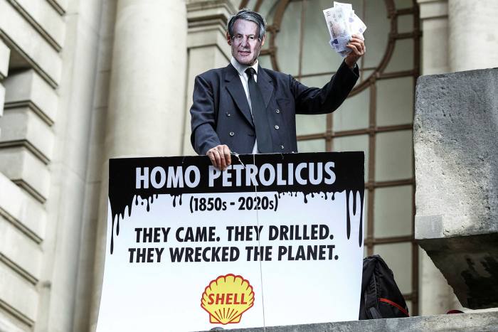 A climate activist wearing a face mask depicting Shell's head, Ben Van Borden, taking part in a demonstration outside Shell's headquarters 