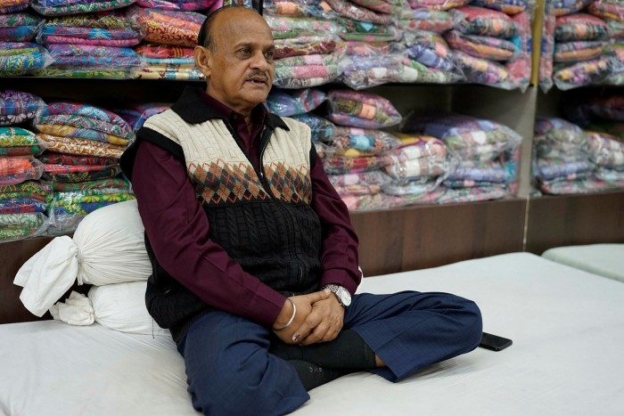 Rakesh Kumar sits cross legged in front of bolts of fabric in the shop he manages
