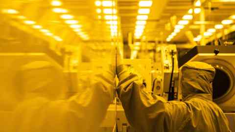 An employee wearing a cleanroom suit performs preventative maintenance inside the GlobalFoundries semiconductor manufacturing facility in Malta, New York