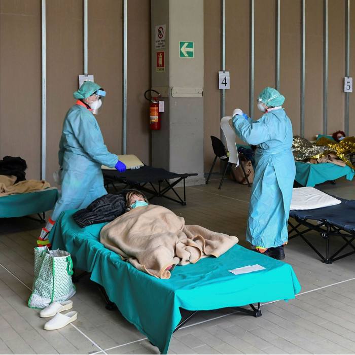 Hospital employees in Lombardy tend to patients lying in bed at a temporary emergency structure set up outside the accident and emergency department in March 2020