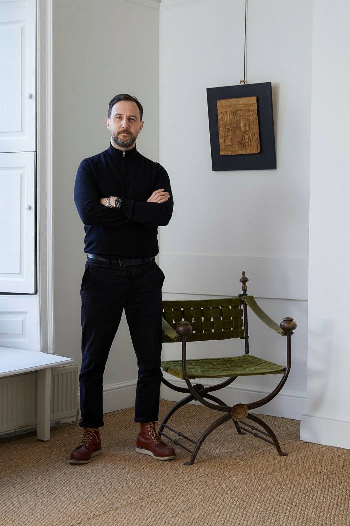 Anthony Kooperman in a white-painted room. He wears dark trousers and polo neck sweater