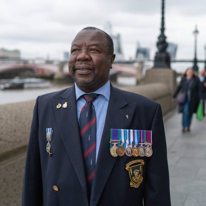 Former soldier Laidley Nelson holds a medal on his chest in a row