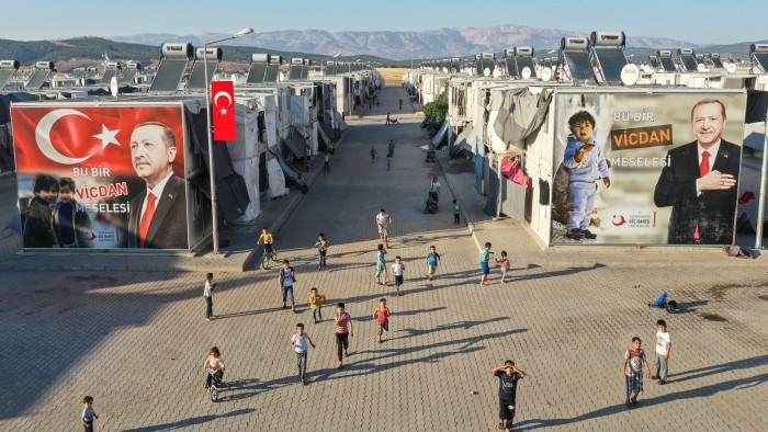 Syrian refugee children play in front of a poster of Turkish President Recep Tayyip Erdogan in the Kahramanmaras refugee camp