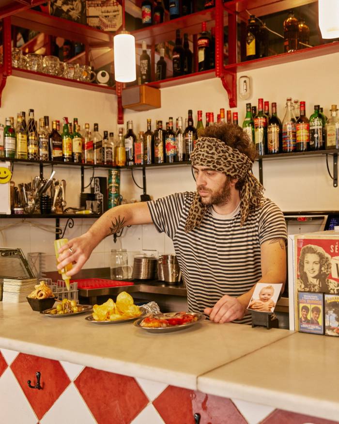  A barman behind La Violeta’s counter seasoning a plate of tapas 