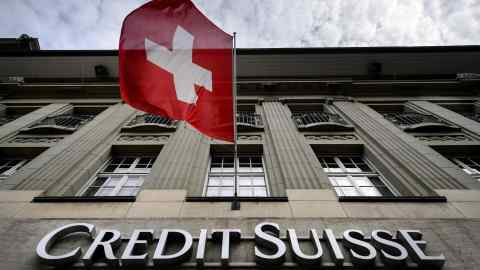 A Swiss flag flies over a sign of Credit Suisse in Bern