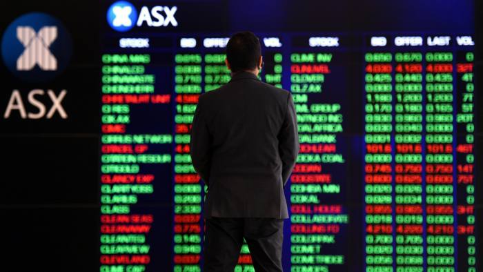 An attendant watches market gains displayed on the Australian Stock Exchange trading board 