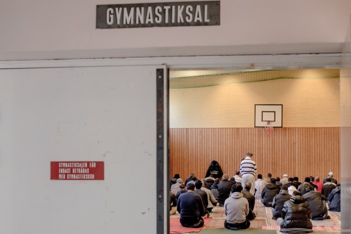 Refugees praying in a gymnasium  