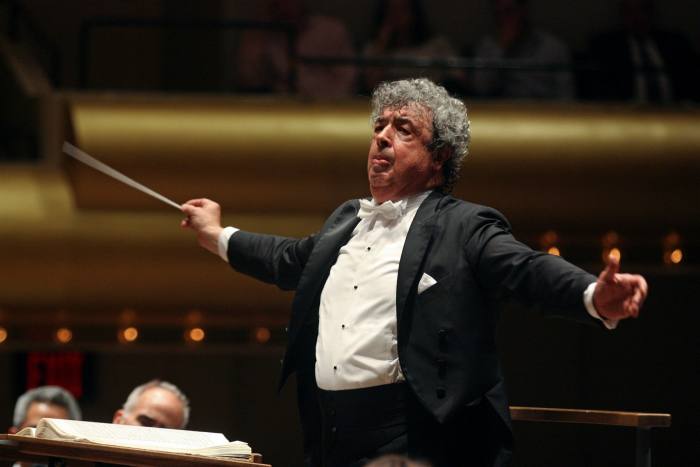 Wearing black jacket and white tie, Bychkov conducts his orchestra 