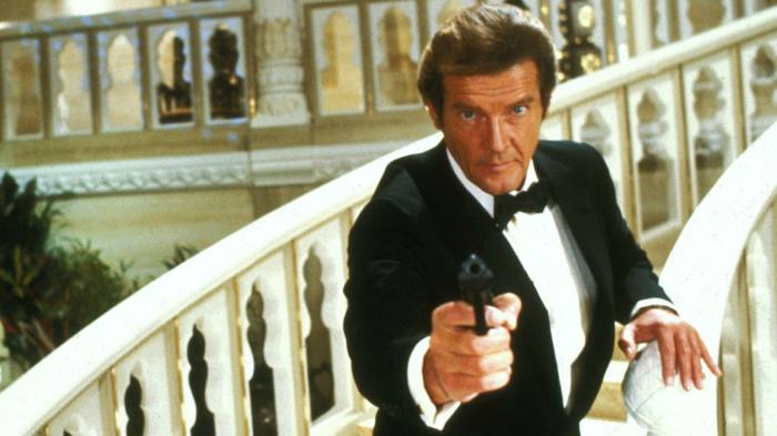 Roger Moore, as James Bond, wearing a tuxedo and standing on a bridge with his pistol drawn