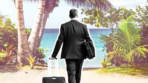 A man in a suit and wheeling a suitcase walks on to a beach