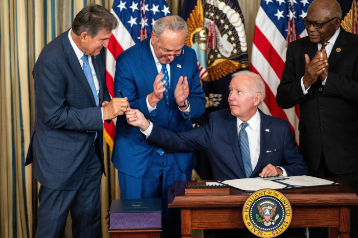 President Joe Biden, center, hands the pen used to sign the Inflation Reduction Act of 2022 into law, to Sen Joe Manchin