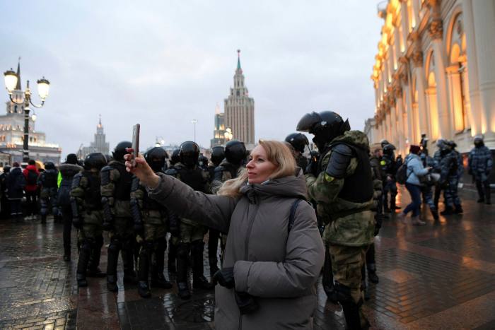 Protester takes photos with her smartphone at a rally in January in support of Alexei Navalny in Moscow in front of law enforcement officials