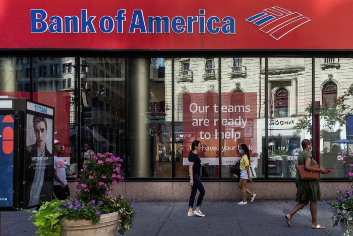 Pedestrians wearing protective masks walk past a Bank of America branch in New York