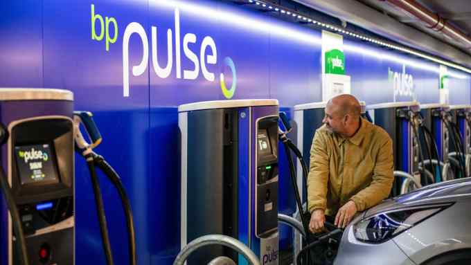 An electric vehicle driver uses a charging point at a BP Pulse charging station