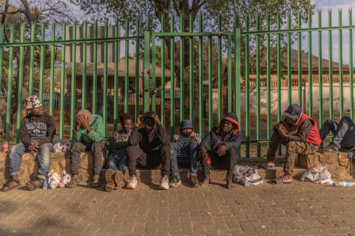 Survivors of the Johannesburg building fire sit outside a provisional shelter