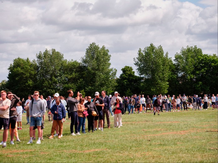 The Queue stretching across a field in Wimbledon Park beneath a cloudy sky