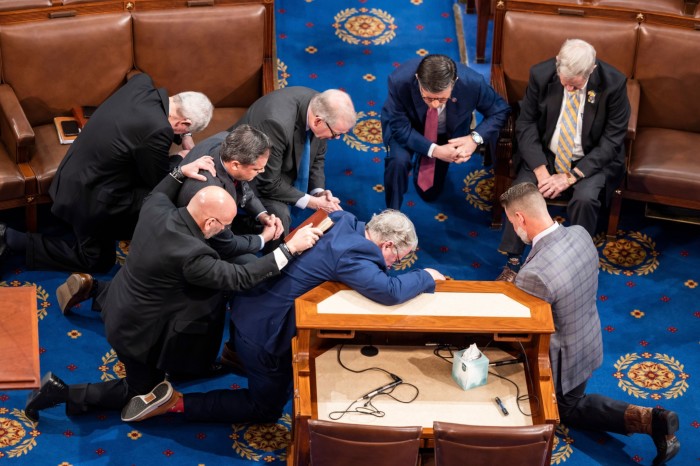 Republican lawmakers pray on the floor of the House of Representatives before another round of voting