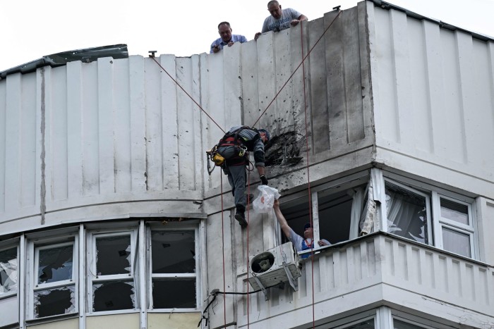 A specialist inspects the damaged facade of a multi-storey apartment building in Moscow