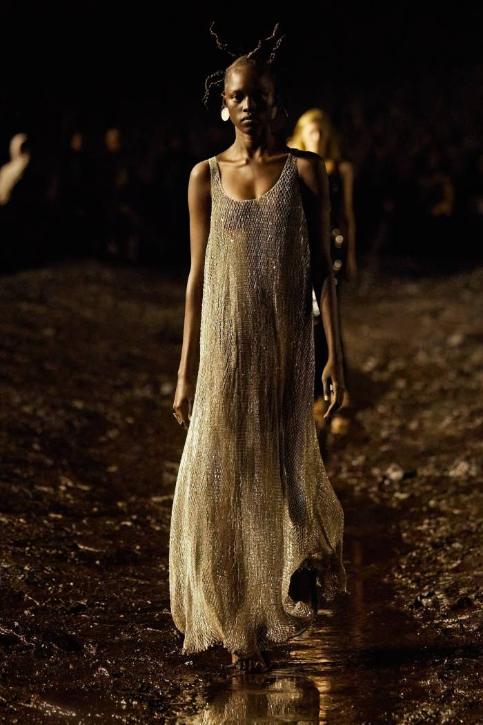 A female catwalk model in a full-length sleeveless evening gown