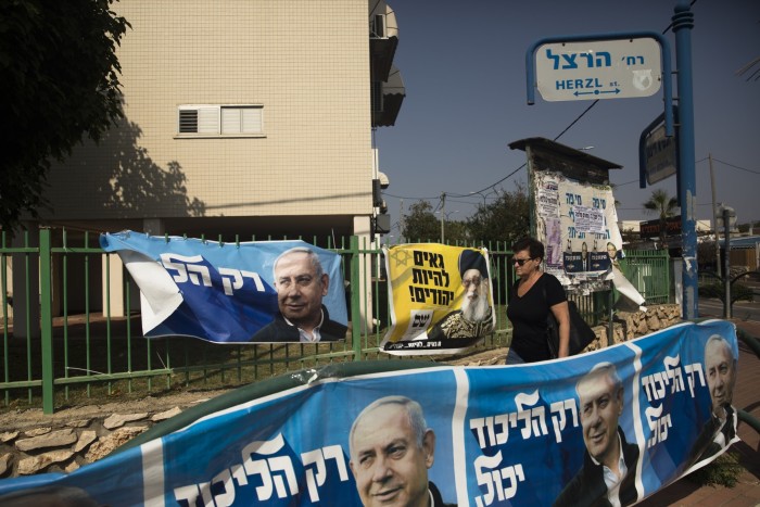 A woman walks campaign posters in Or Akiva, Israel, in October 2022