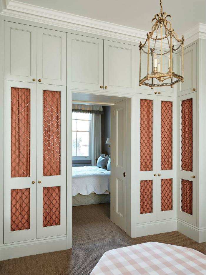 Wardrobe with panels of coral-colored gathered fabric behind lattice metalwork