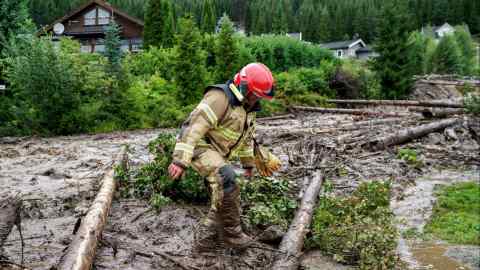 A firefighter wades through mud after a landslide in Valdres, Norway, on Tuesday
