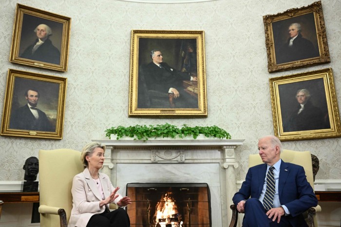 Ursula von der Leyen and Joe Biden sit in armchairs on either side of a fireplace in the Oval Office