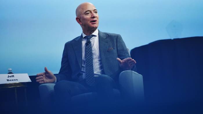 Amazon chief Jeff Bezos wearing a suit, sitting on a sofa