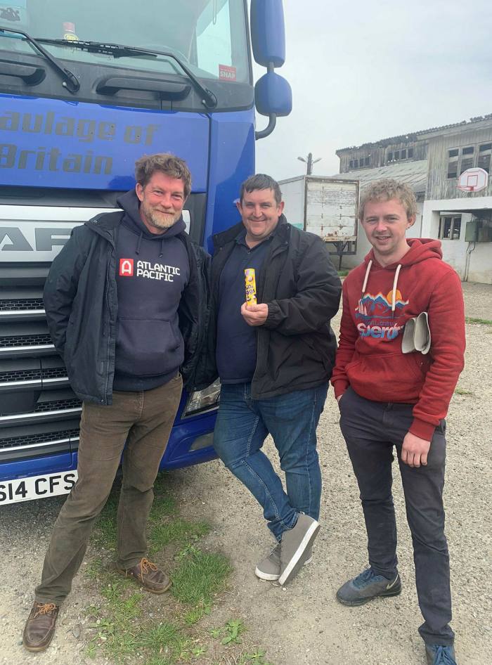 Horatio Clare, Ian Payne and Charlie Bailey stand smiling next to a blue lorry at the Romanian-Ukrainian border