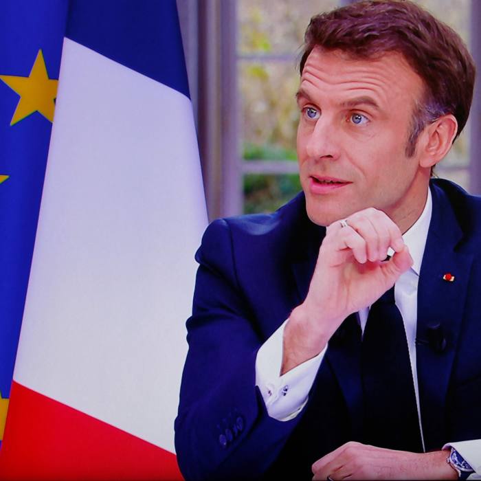 Emmanuel Macron at his desk next to the French flag