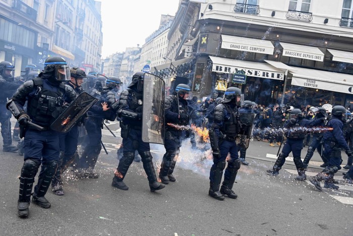 French riot police officers stand guard during a demonstration against pension reforms in Paris