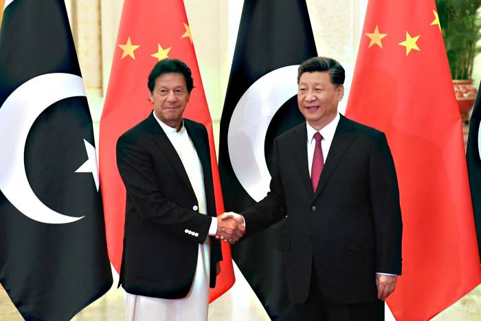 Imran Khan and Xi Jinping shake hands in front of their country’s flags